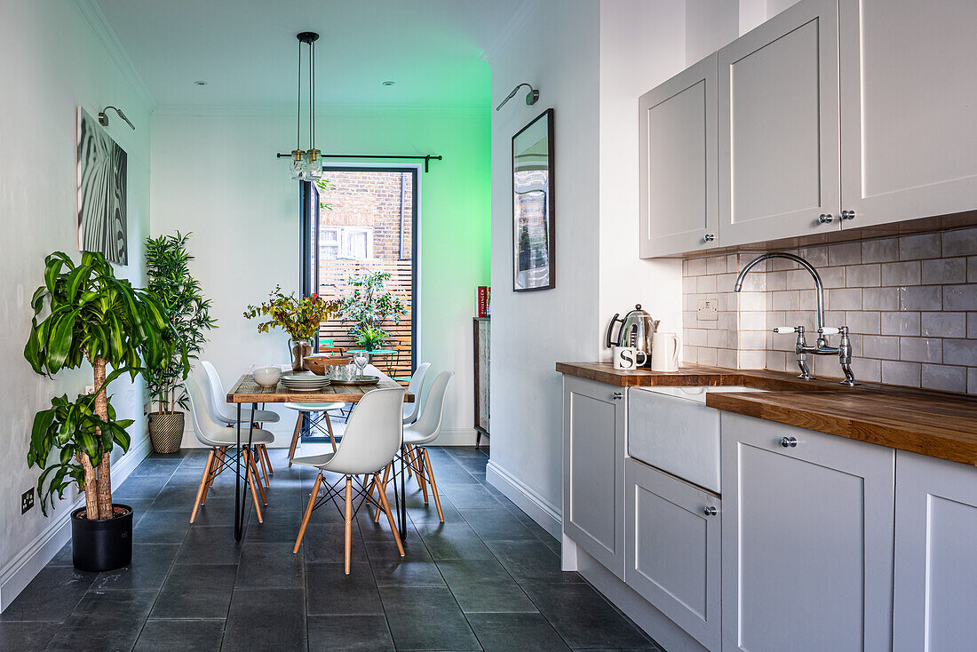 Esstisch in der Wohnküche mit grauer Küchenzeile und Pflanzen