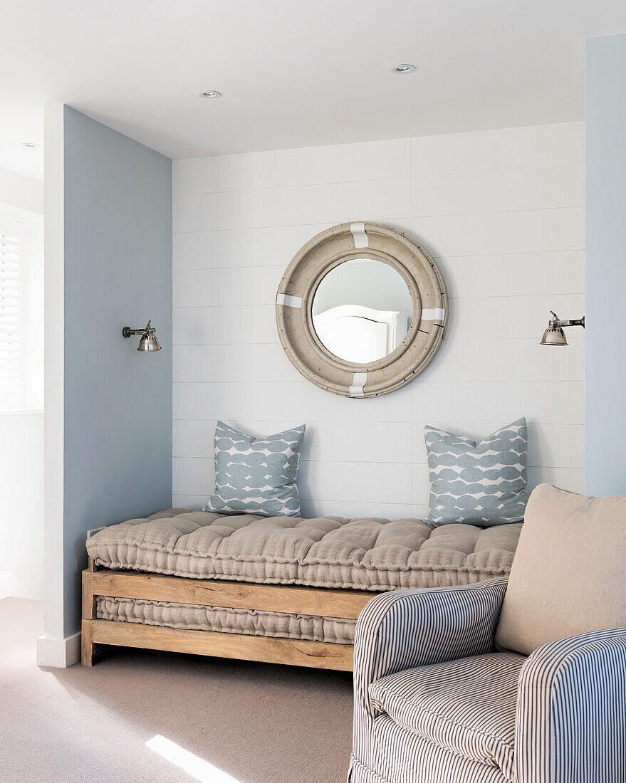 Tagesbett aus Holz mit kapitonierte Auflage, kleine Wandleuchten aus Zinn und runder Wandspiegel
