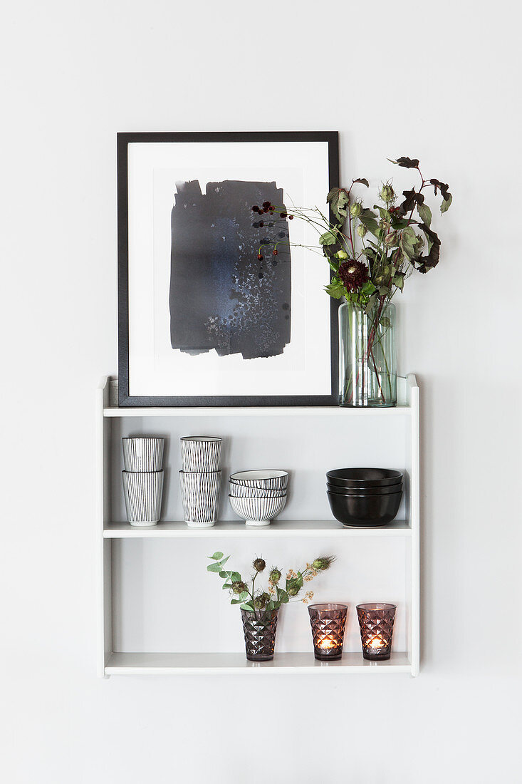 Bowls, beakers, flowers, tealight holders and picture on wall-mounted shelves