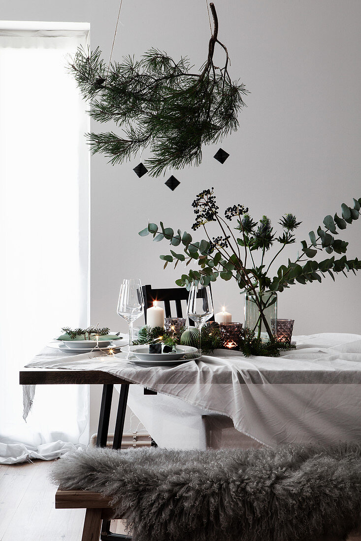 Christmas table decoration with a pine branch and a bouquet of eucalyptus and Eryngo