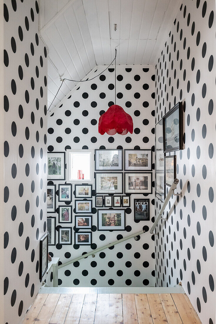 Polka-dot wallpaper on landing with staircase and gallery of pictures on wall