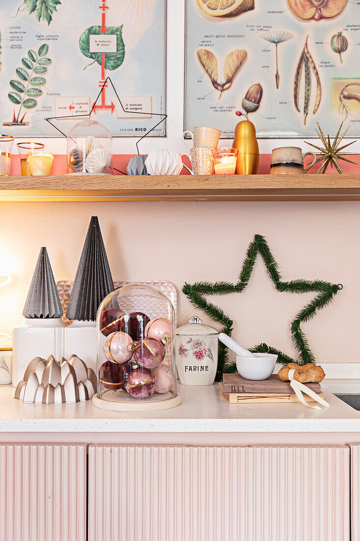 Christmas decorations on pink kitchen cabinets, open shelving above it