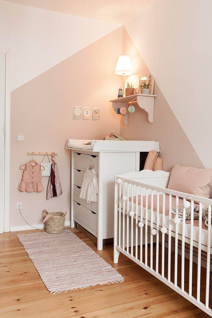 Babyzimmer mit Bettchen und Wickelkommode in Weiß und Rosa