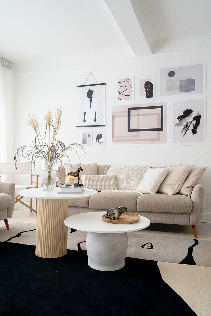 Helles Wohnzimmer mit Couchtischen, Sofa in Beige, darüber moderne Kunst