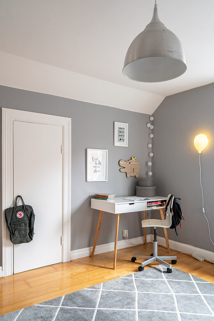 Schreibtisch mit Drehstuhl in Kinderzimmerecke mit grauen Wänden