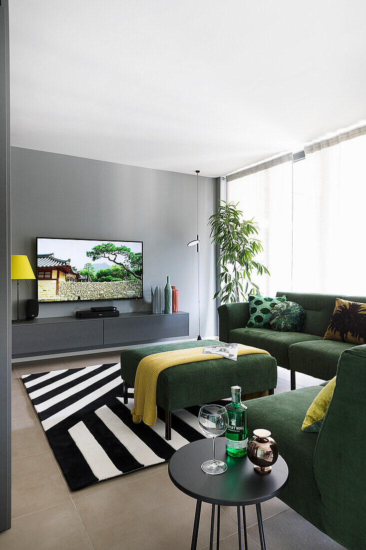 Grünes Ecksofa, Beistelltisch, Ottoman, Hängeboard und Fernseher im Wohnzimmer