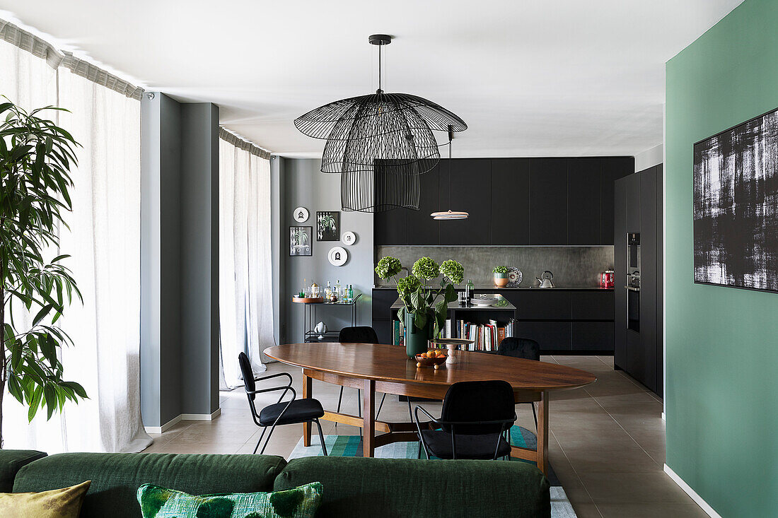 Open plan living room with black fitted kitchen cabinets, dining area, and green sofa