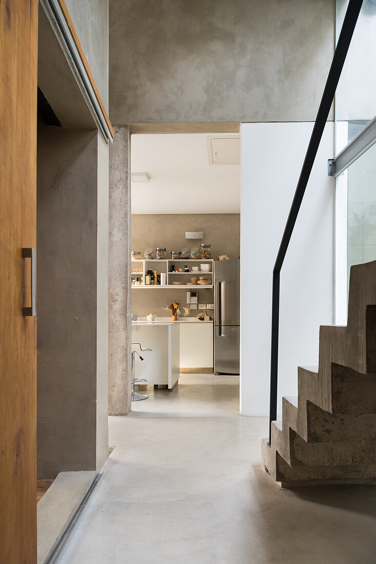 Blick vom Flur mit Betonboden und Treppe in die Küche