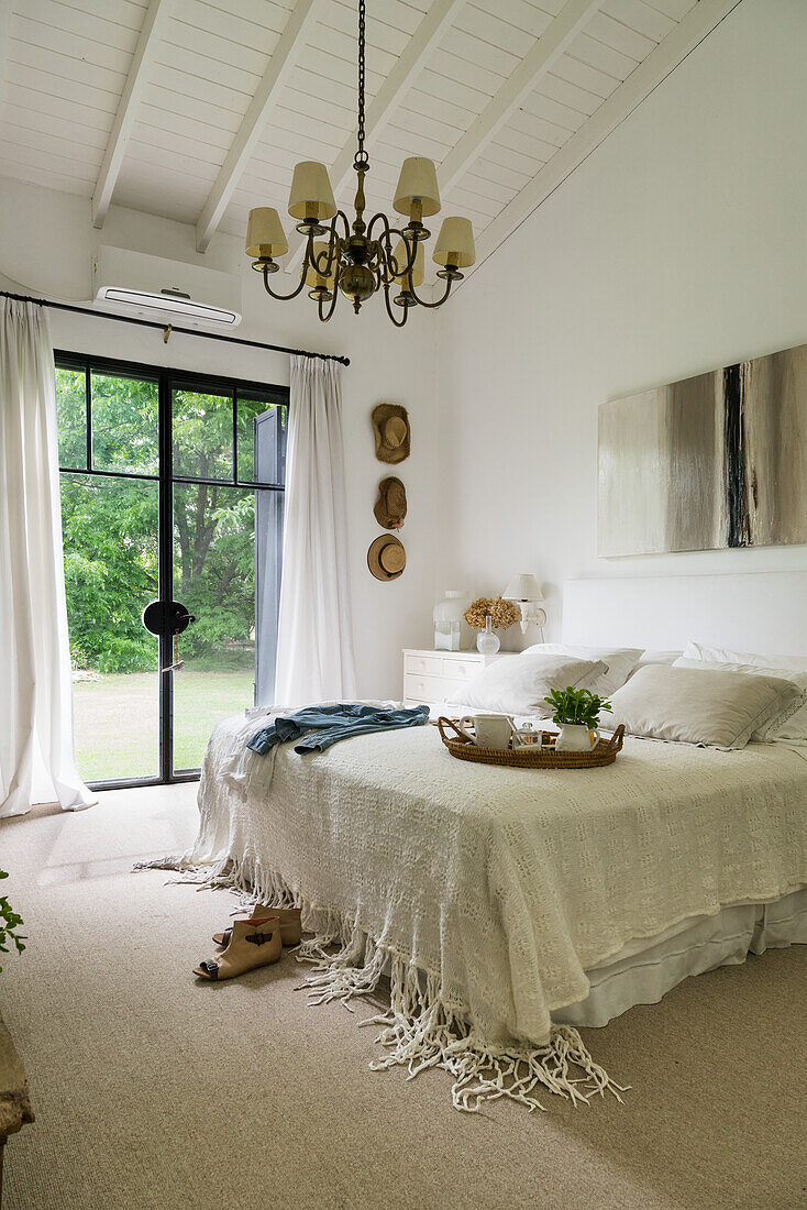 Doppelbett mit weißer Tagesdecke in ländlichem Schlafzimmer