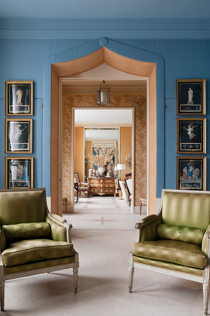 A pair of Louis-XVI armchairs in front of doorway framed by regency artworks