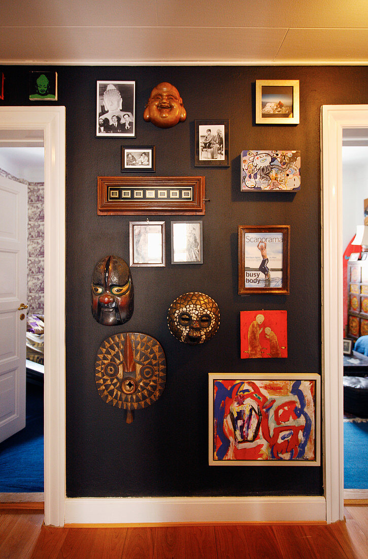 Masken, Spiegel, Rahmen, Gemälde, Fotos an schwarzer Wand auf dem Flur