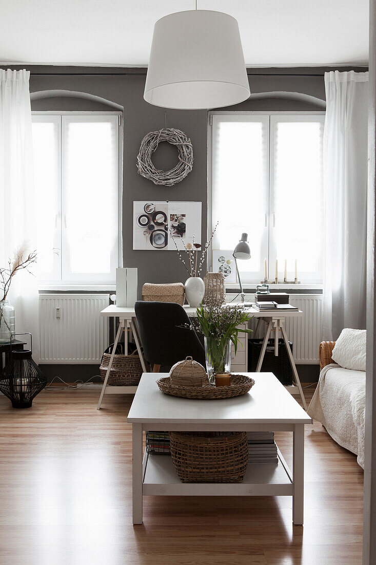 Weißer Couchtisch, im Hintergrund Schreibtisch im Wohnzimmer mit grauer Wand