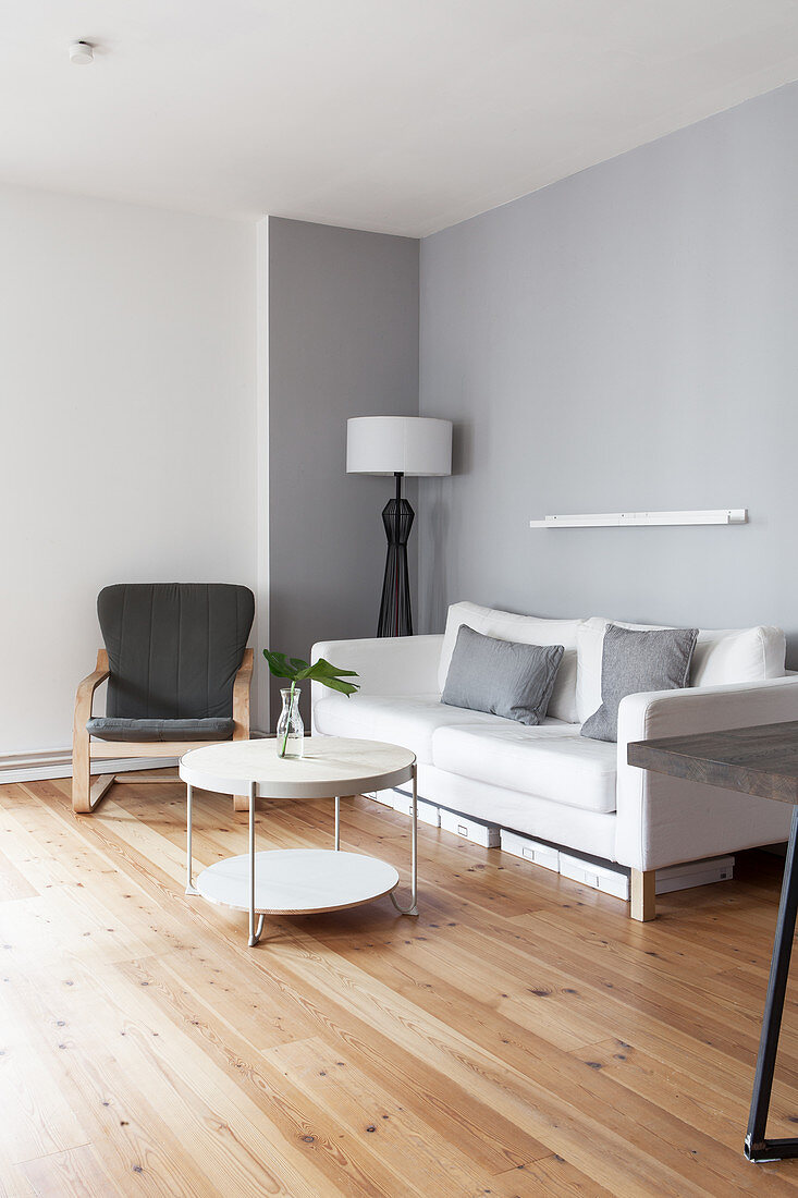 Weißes Sofa, Sessel und runder Couchtisch im grau-weißem Wohnzimmer