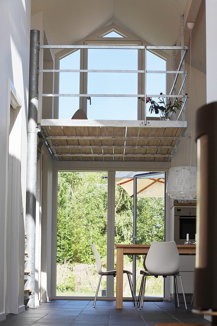 Esstisch mit weißen Stühlen im Erdgeschoss, in transparentem Haus