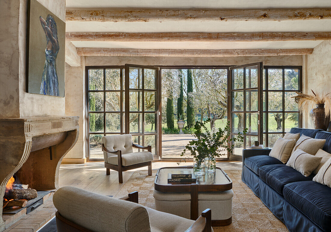 Living room with natural stone fireplace, comfortable seating, exposed wooden beams and terrace access
