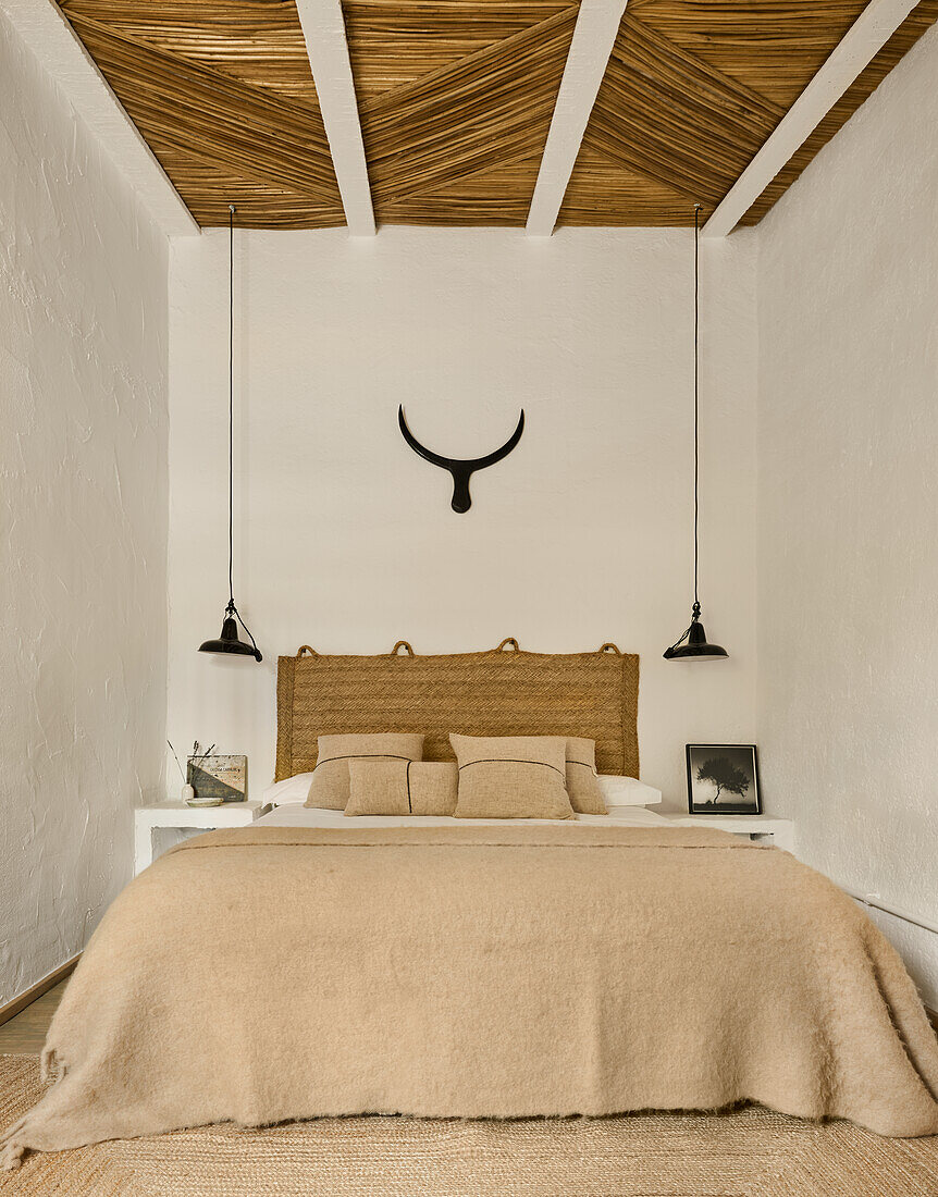 Doppelbett mit Naturteppich als Bettkopfende im Schlafzimmer mit Schilfrohrdecke