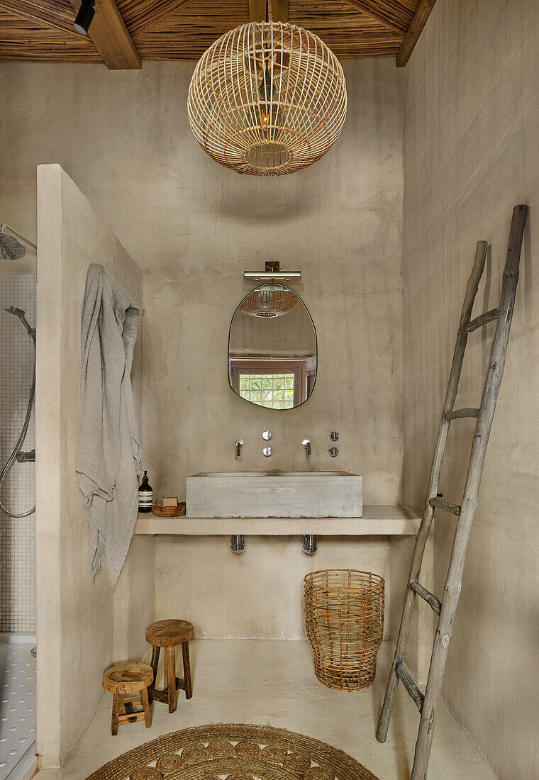 Washstand next to shower area and towel dryer in bathroom with sand-colored walls