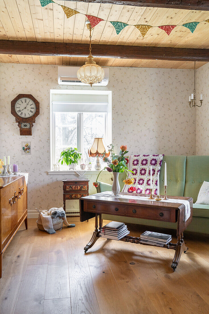 Cochtisch vor grünem Sofa in ländlichem Wohnzimmer mit Tapete