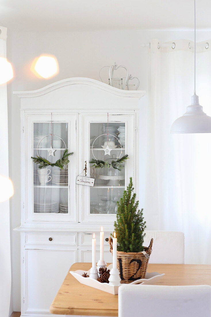 A dining table with Christmas decorations in front of a white sideboard