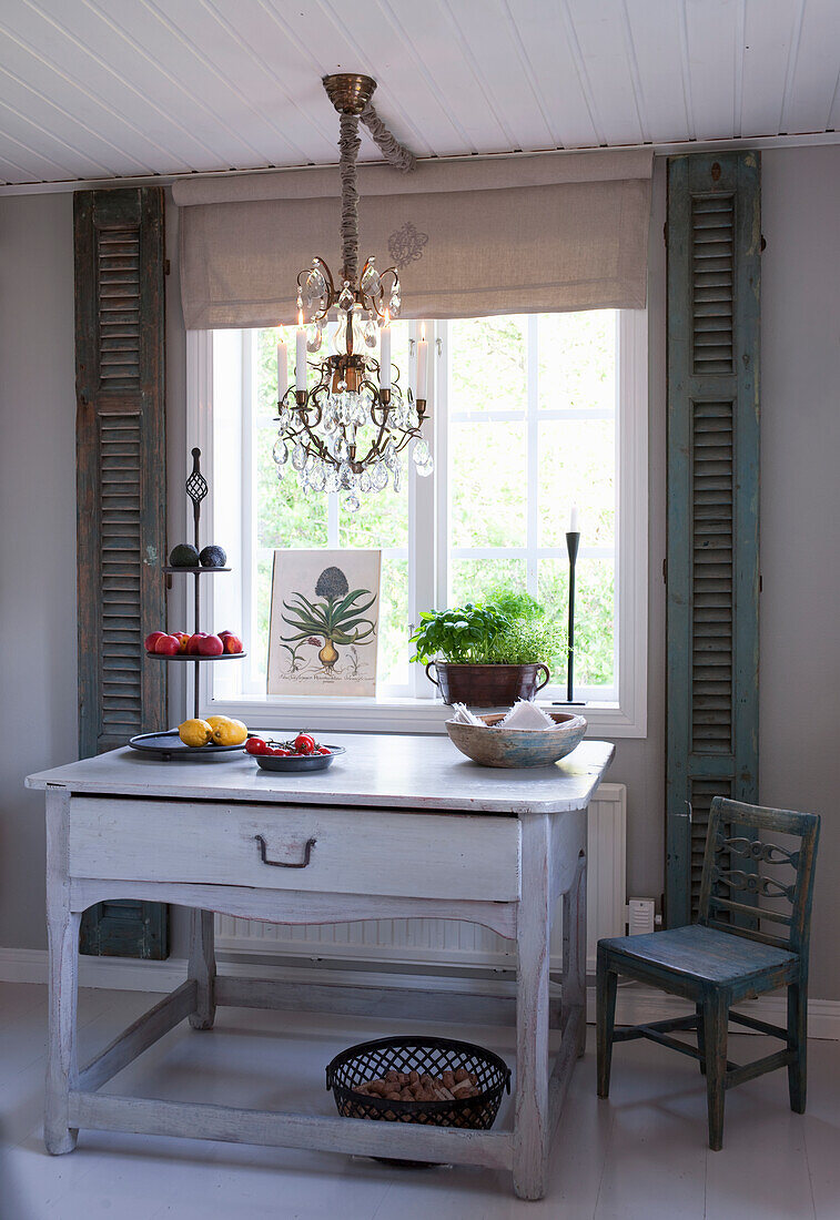 Old kitchen table with drawers, above it a chandelier