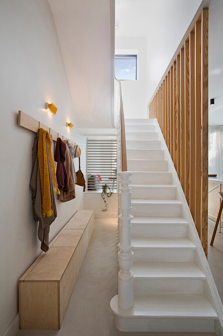 Weiße Treppen und Holzsprossen, Sitzbank als Stauraum und Garderobenleiste