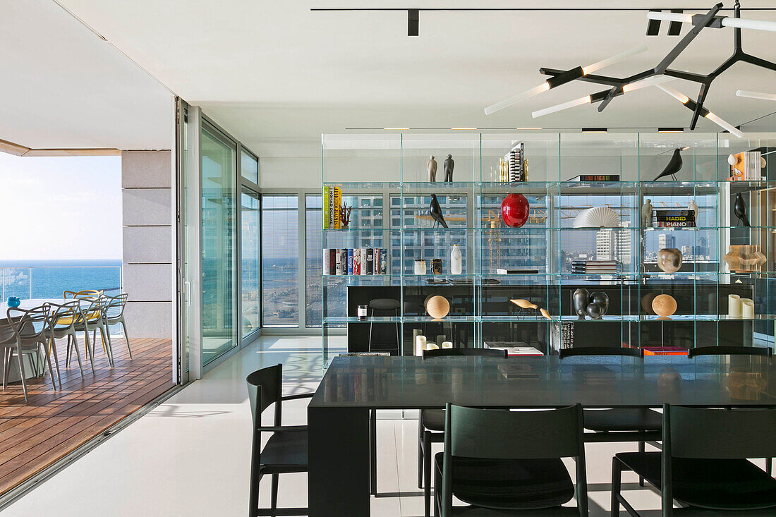 Schwarzer Esstisch mit Stühlen vor offener Terrasse in einem Luxus-Penthouse