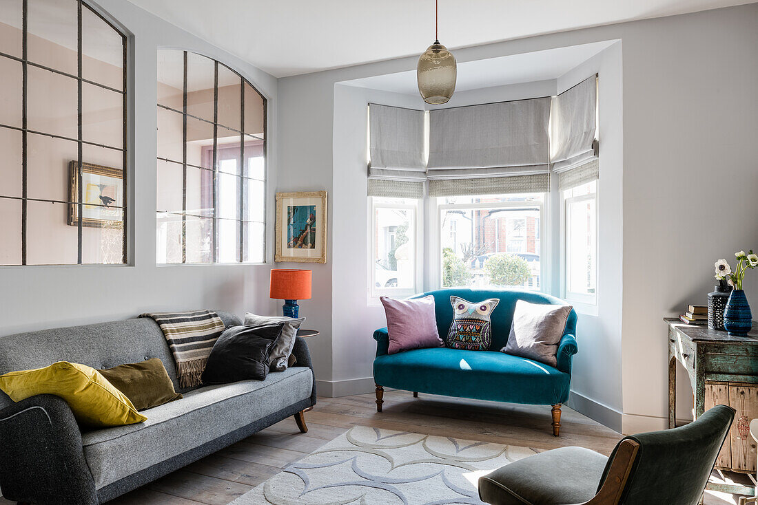 Große französische Metallfenster im Wohnzimmer mit grauem Vintage-Sofa und kleinem Polstersofa