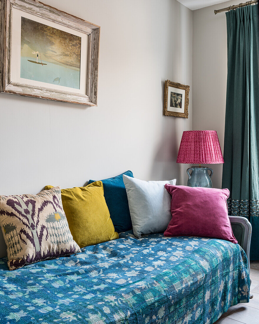 Quilted kantha throw on daybed with an assortment of brightly coloured velvet and ikat cushions