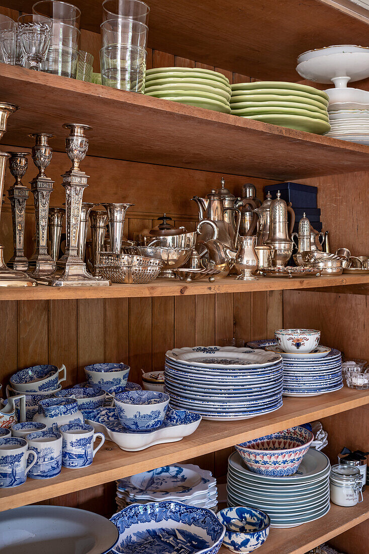 Blau-weißes Porzellan und Silberware auf Holzregalen