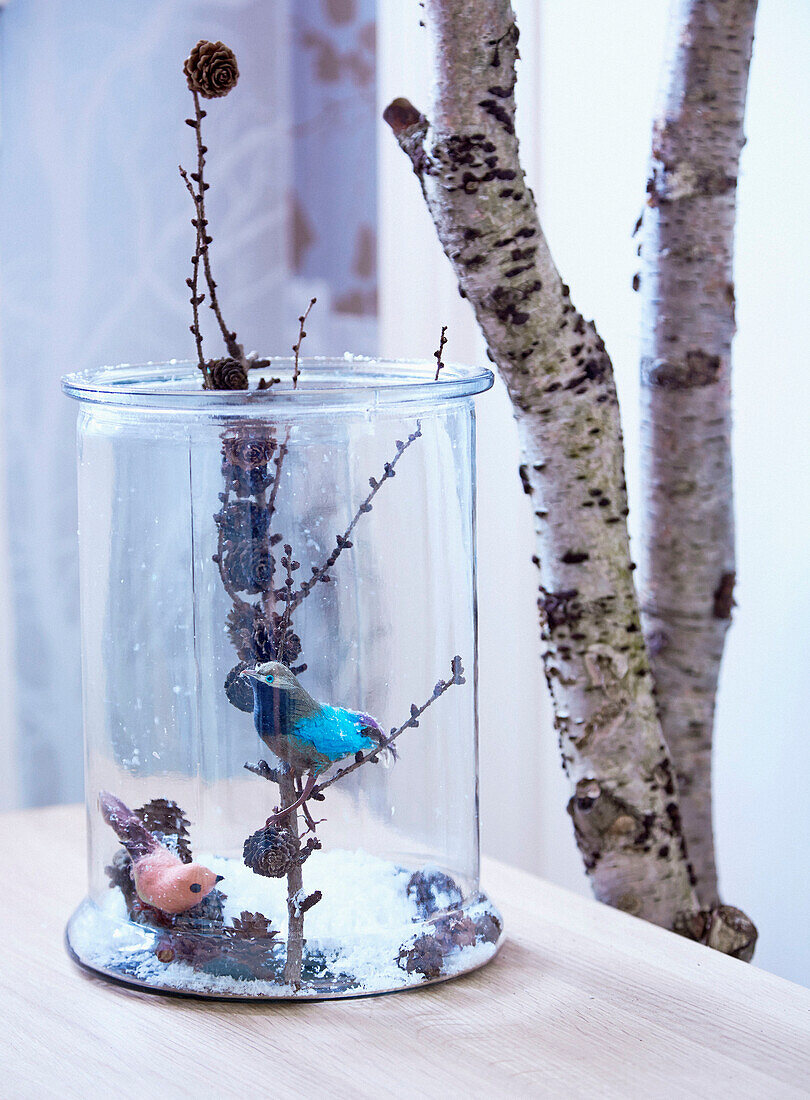 Larch branch and decorative birds in glass jar