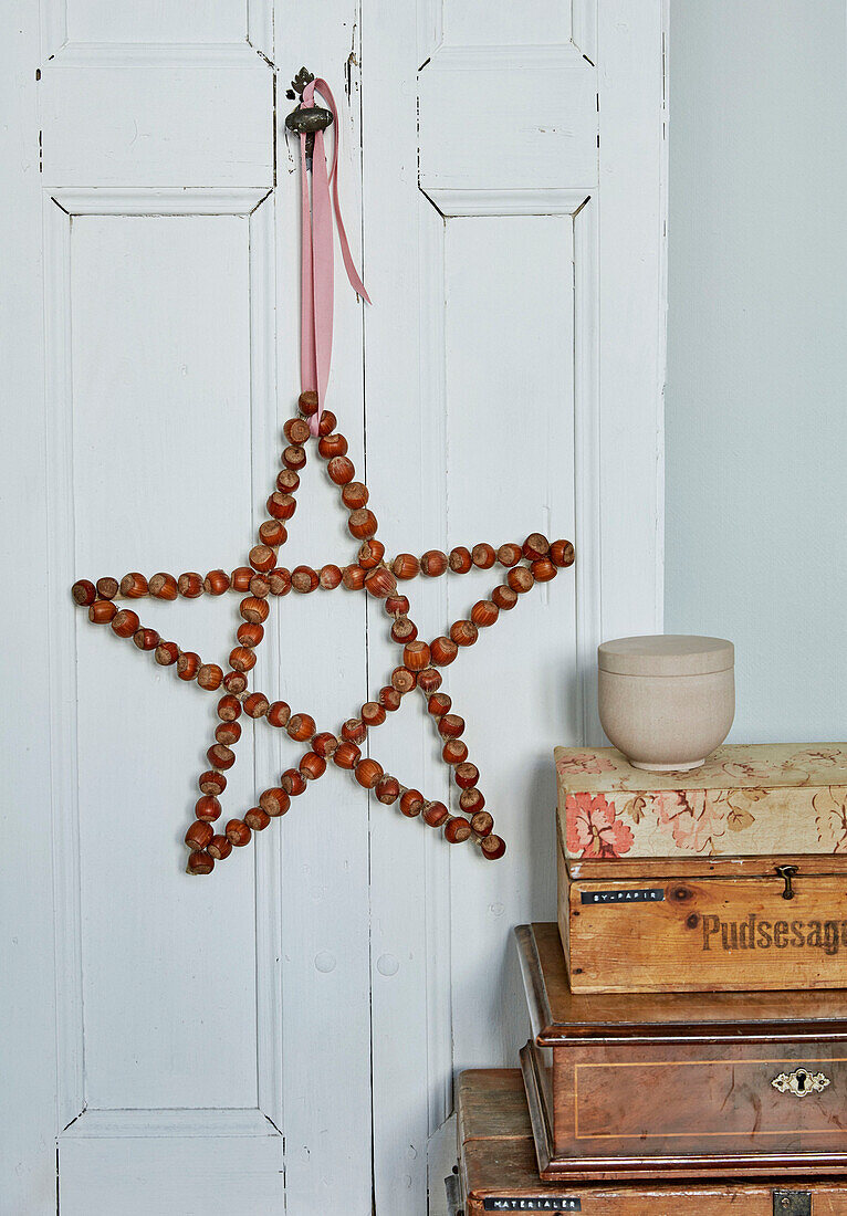Star made of hazelnuts with decorative ribbon on door handle