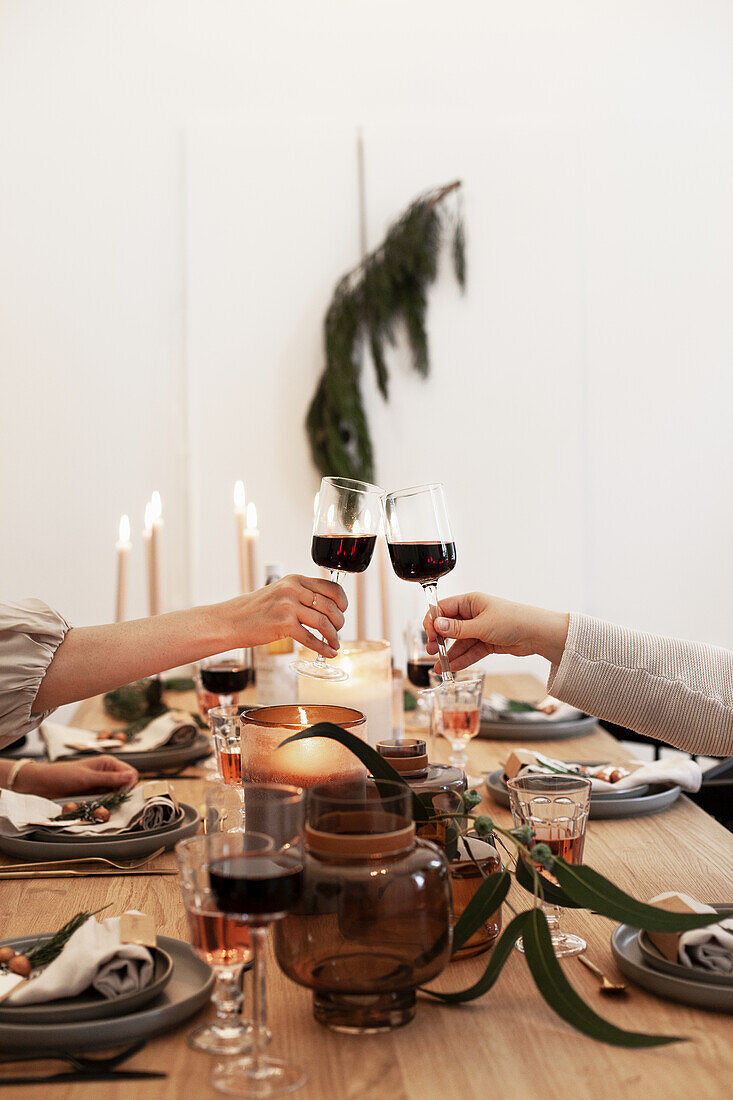 Christmas table setting, hands toasting with red wine