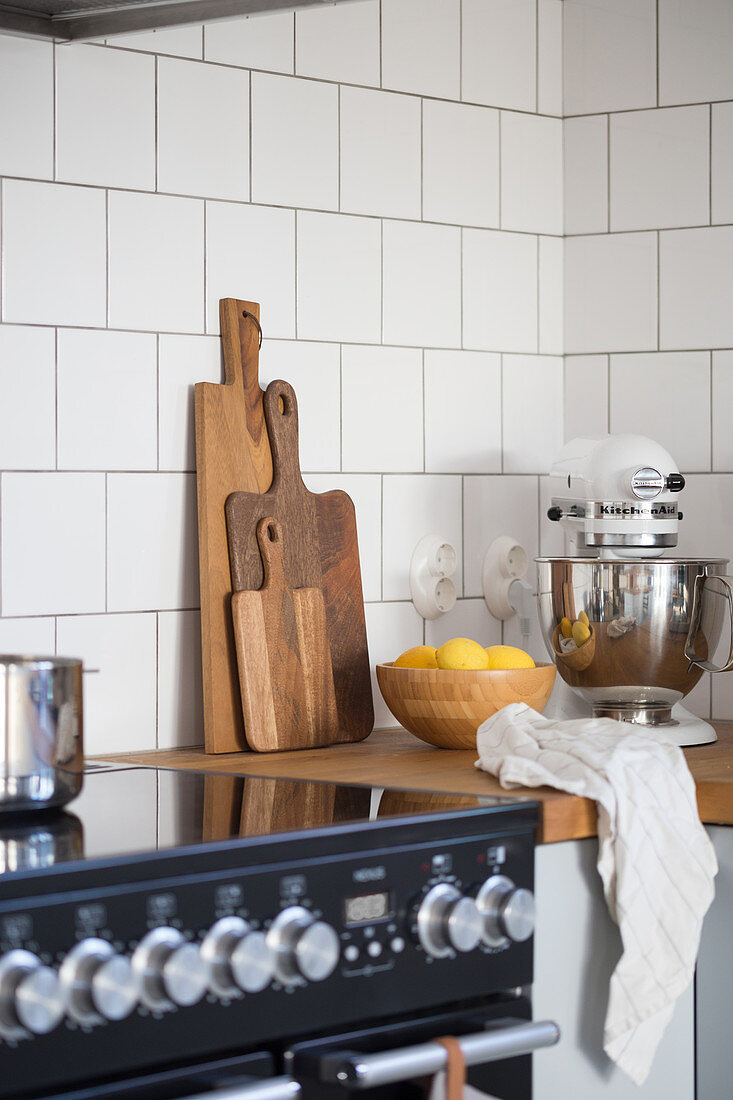 A kitchen corner with a wooden worktop, chopping boards, a food processor and a fruit bowl
