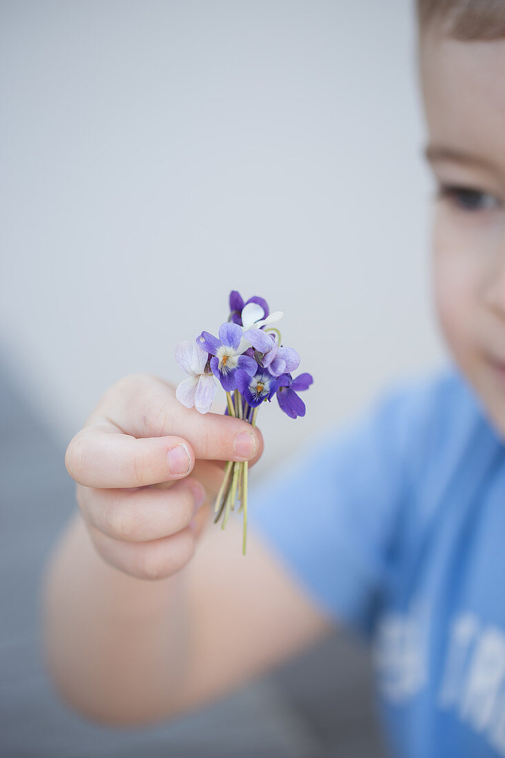 A boy holding a bouquet of violet flowers