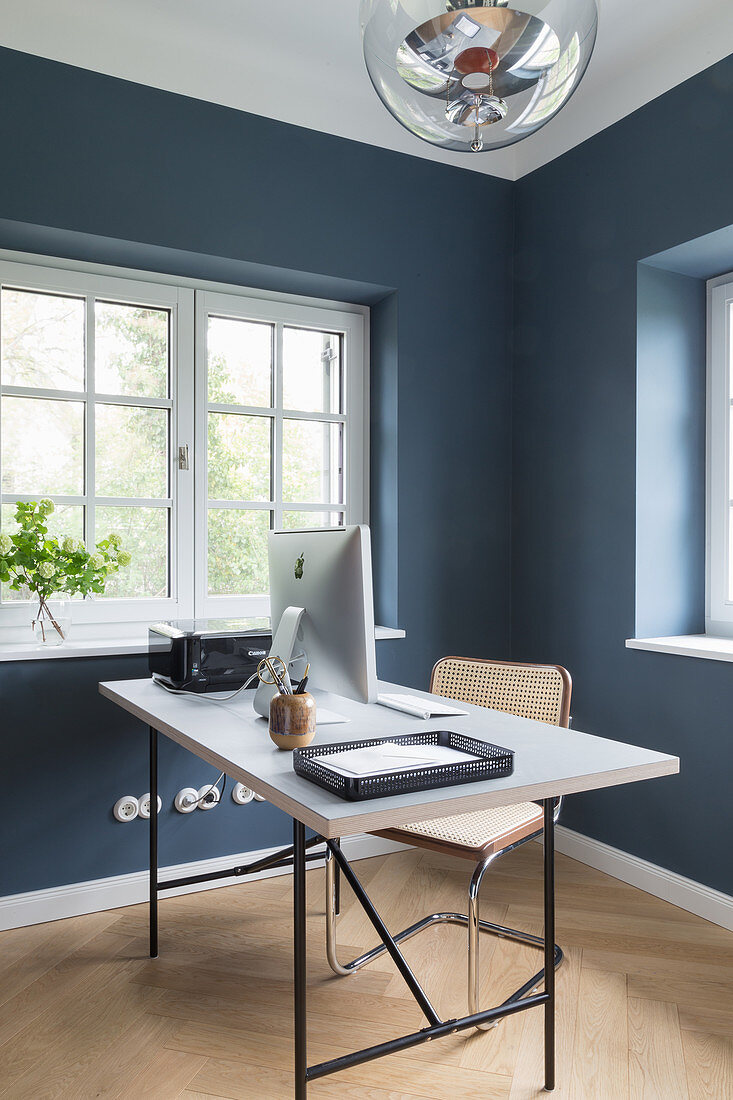 Schreibtisch mit Bildschirm im Arbeitszimmer mit blauen Wänden