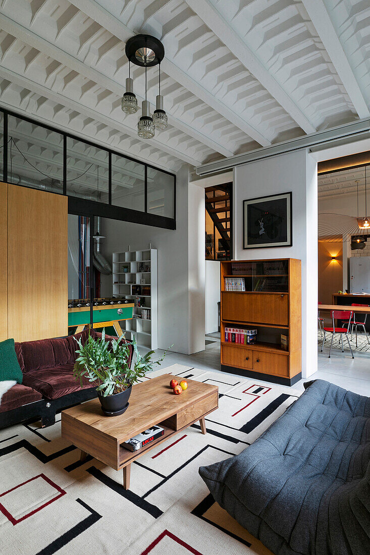 Sofas and coffee table in front of wooden wall and retro highboard in a loft