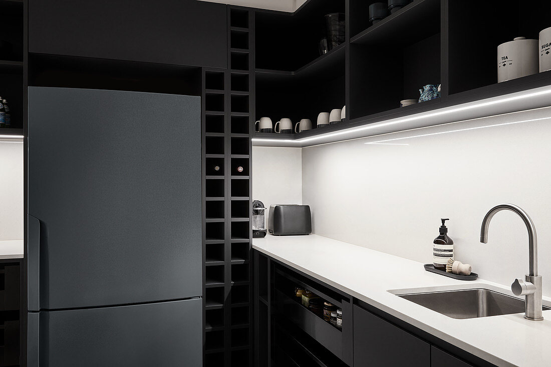 Kühlschrank in schwarzer Küche mit weißer Rückwand