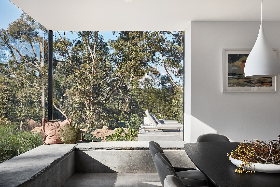 Elegant dining area with masonry window seat running along panoramic glass walls