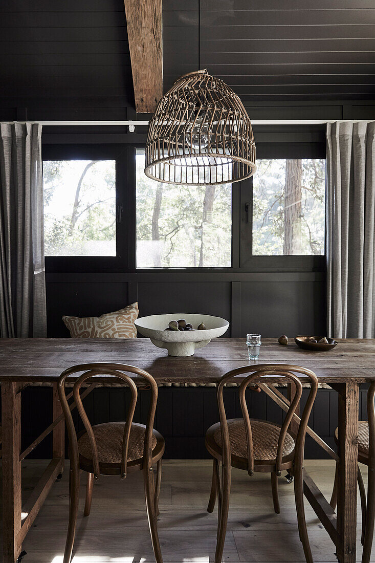 Wooden table with chairs in dining room with dark wall