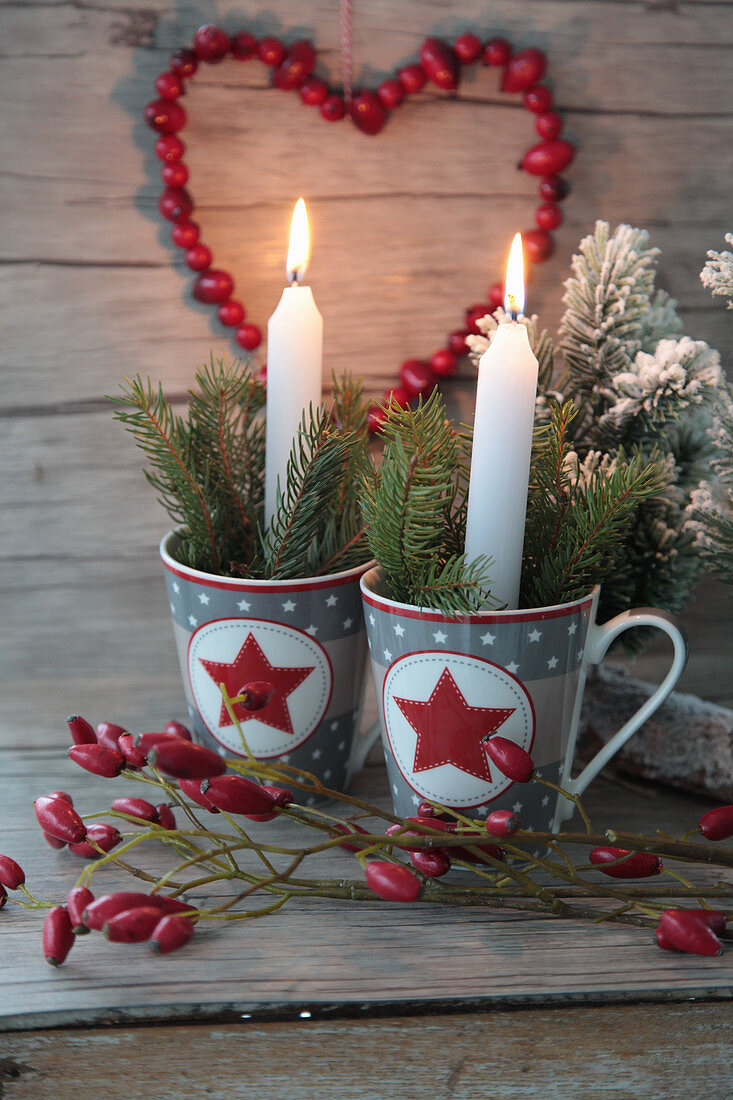 Candles and twigs in Christmas cups with a rose hip heart