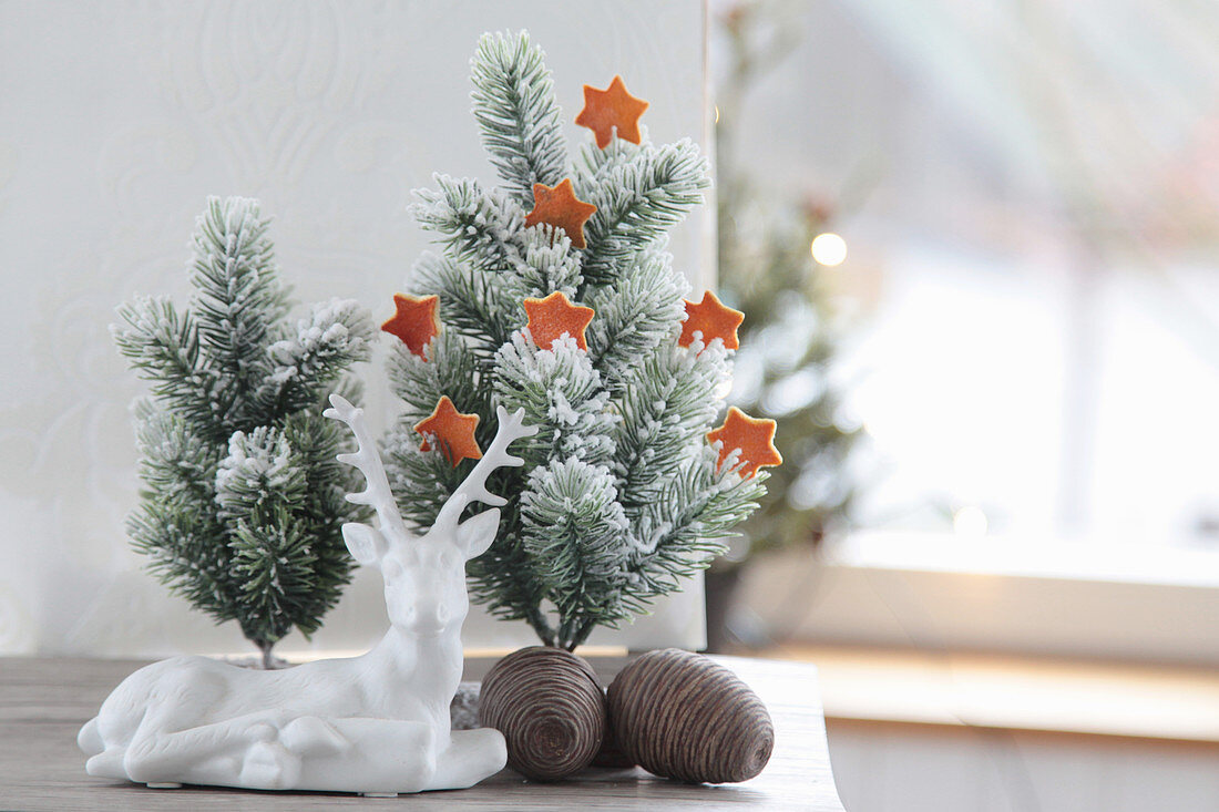 Tiny Christmas tree with stars made of orange peel, ceramic deer and cones