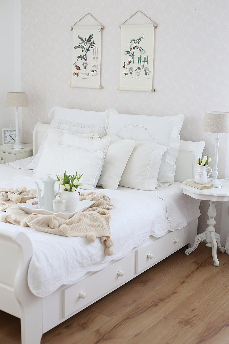 White bed with collection of scatter cushions, tray and bouquet of tulips