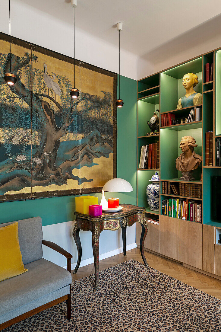 Großformatiges Kunstwerk und Bücherregal mit Büsten im Salon mit grünen Wänden