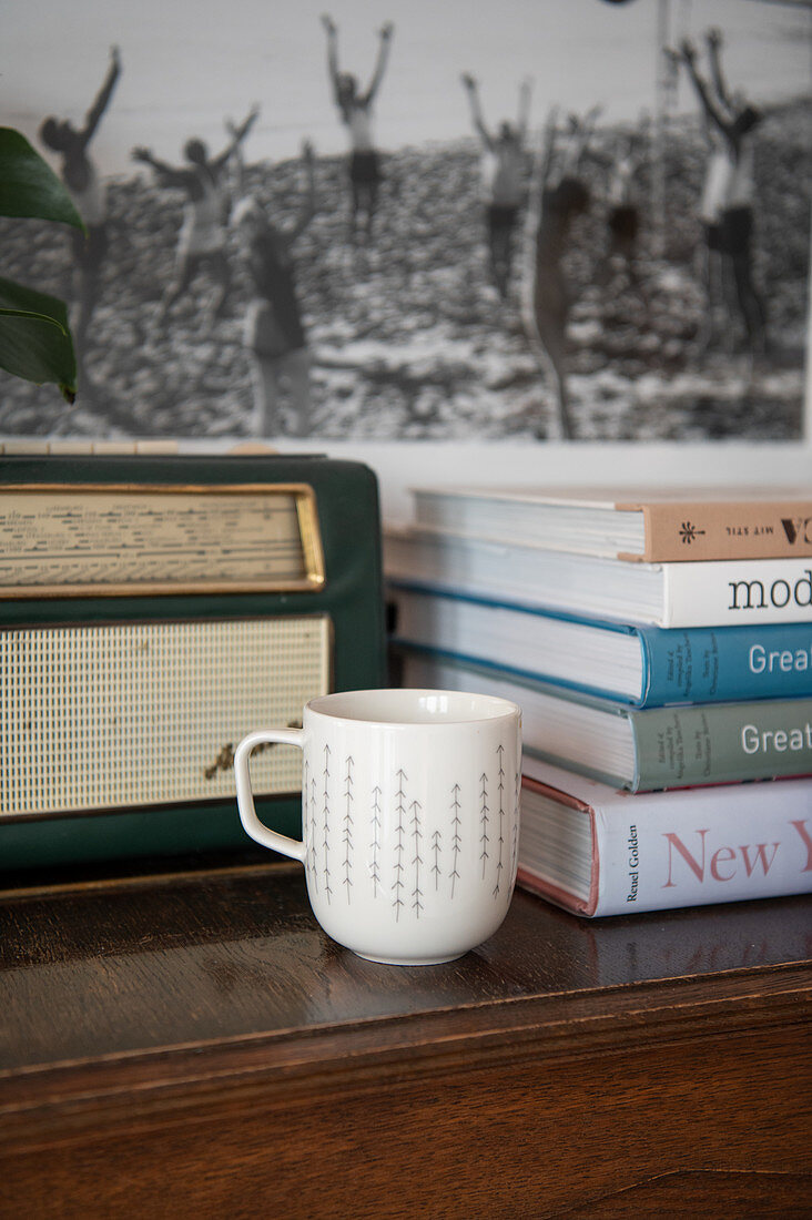Kaffeebecher vor Bücherstapel und Retro Radio