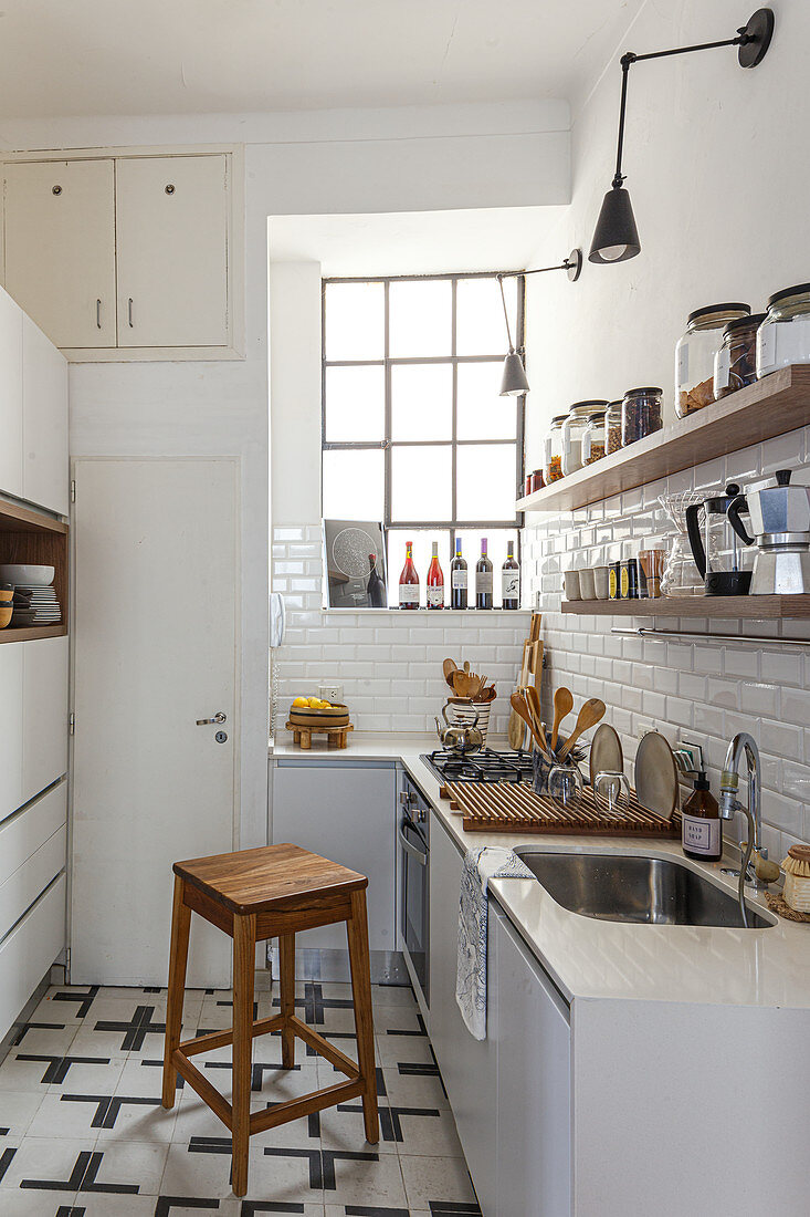 Schmale Küche mit weißen U-Bahnfliesen, Holzregalen, Sprossenfenster und Holzhocker