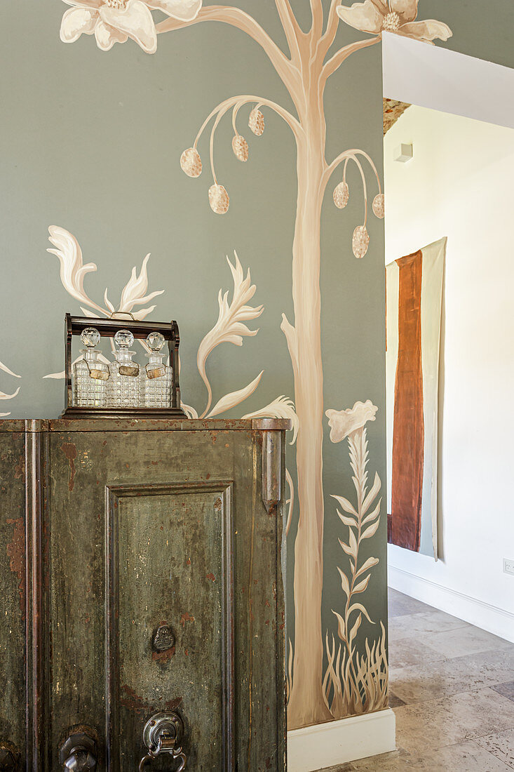 Vintage cabinet in room with mural of tree on wall
