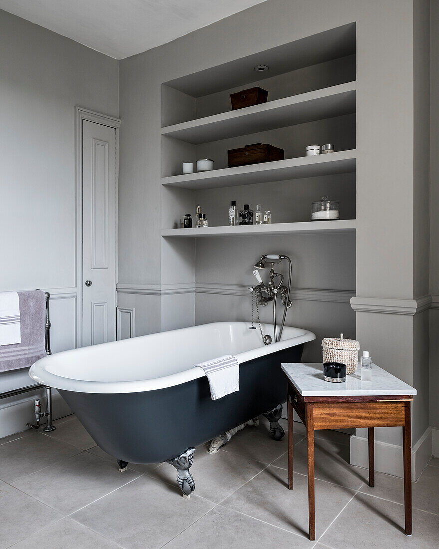 Freistehende Badewanne unterm Regal im klassischen Bad in Grau