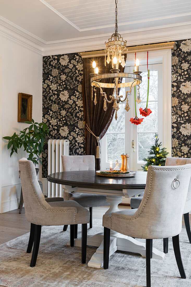Elegantes Esszimmer mit rundem Tisch und Polsterstühle, im Hintergrund eine Wand mit Blumentapete