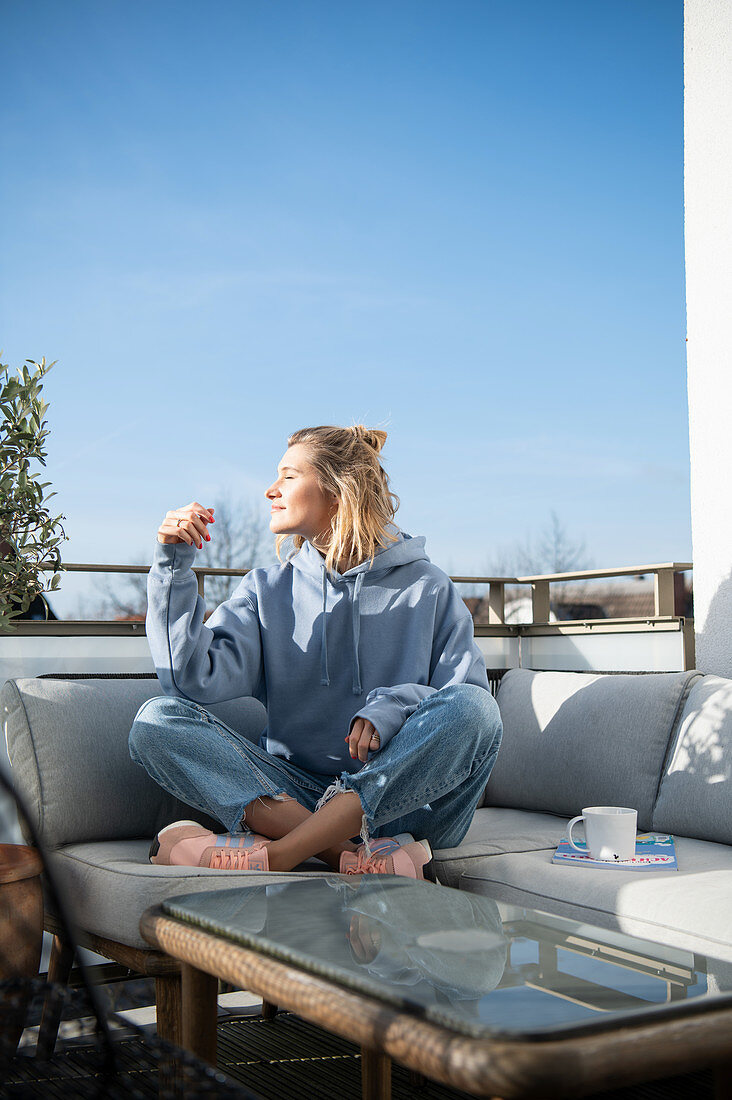 Blonde woman in casual wear is sitting on the terrace