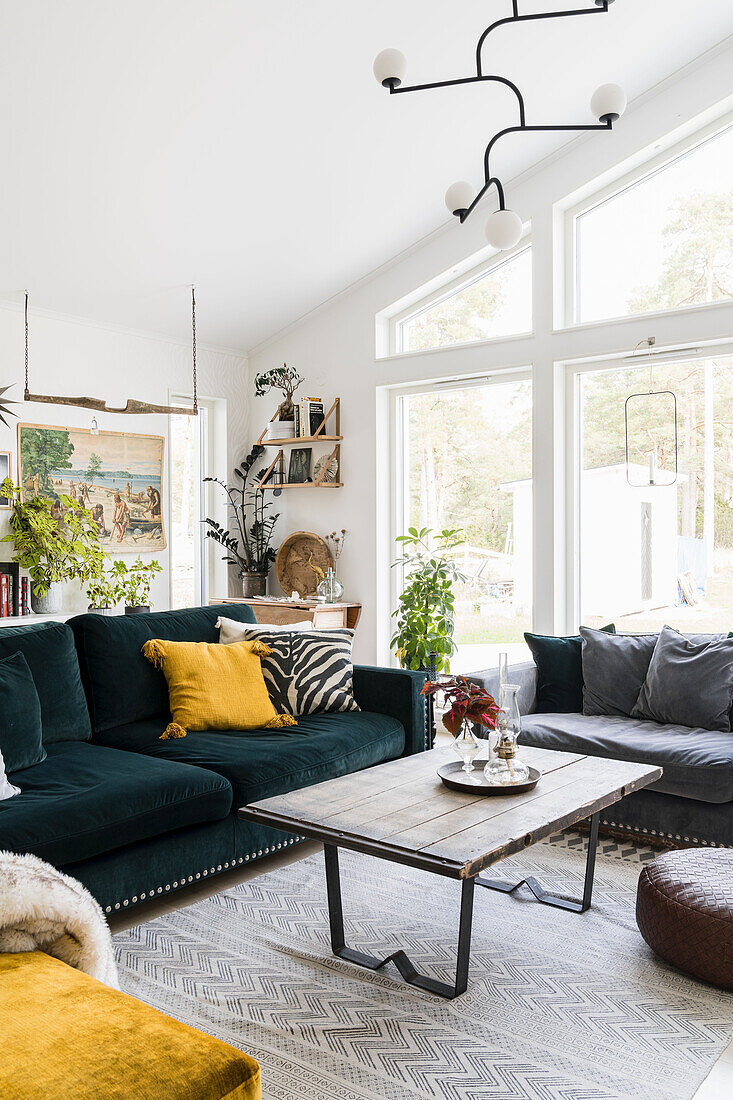 Petrol colored sofa with cushions and vintage coffee table with wooden top in the living room
